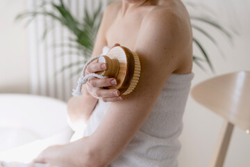 Woman using wooden brush for dry massage at home