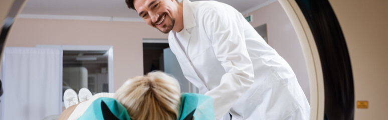 radiologist in white coat smiling near woman and computed tomography machine, banner.