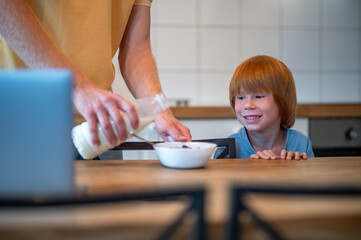 Obraz na płótnie Canvas Man pouring milk into the plate of his son