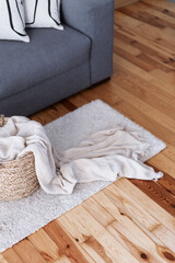 Fototapeta na wymiar soft plaid in wicker basket on floor rug in living room