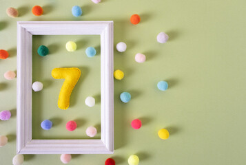 The number Seven for a birthday in a white frame with colored balls. Festive concert, party, anniversary