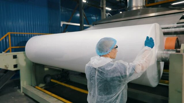 A man checks the quality of the snapon at the factory. Factory quality control. Sintepon production. industrial interior
