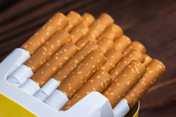 Cigarettes in a pack. Yellow filter. Harm to health. Bad habit. A pack of cigarettes on the table.