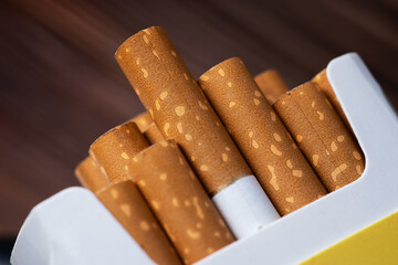 Cigarettes in a pack. Yellow filter. Harm to health. Bad habit. A pack of cigarettes on the table.