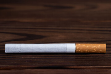 The cigarette on a wooden background close up