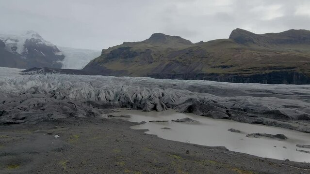 Drone flying over Svinafellsjokull glacier tongue with mountain in background, Iceland. Aerial forward 
