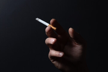 Close up man hand smoking cigarette on black background.