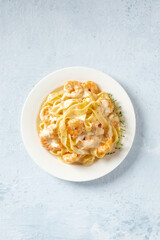 Seafood pasta. Pappardelle with shrimps and cream sauce in a white plate, with fresh thyme, overhead flat lay shot with copy space
