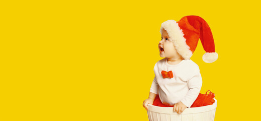 Portrait of happy smiling little child in christmas santa red hat playing with toys on yellow background