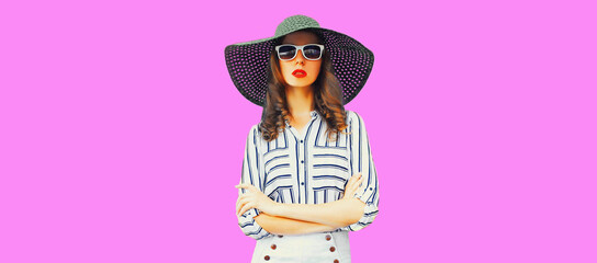 Portrait of beautiful woman model wearing black round summer straw hat, white striped shirt on pink background