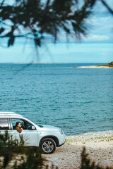 woman in white suv car at sea beach. bay on background