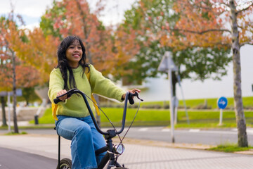 Young asian female student with backpack cycling on her way to college in autumn, healthy life, eco friendly