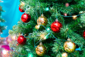 the Christmas tree is decorated with red and gold shiny balls and a glowing electric garland