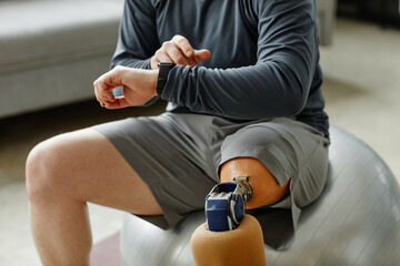 Close up of man with prosthetic leg checking smartwatch during workout, copy space