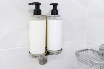 Fototapeta na wymiar Mockup of two white shampoo dispenser bottles in the bathroom. The concept of hair and body care products