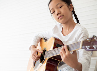 Talented female musician playing acoustic guitar on white background. Young asian guitarist put...