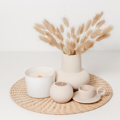 Vase with lagurus grass and candle set home decoration, candle in glass jar with ceramic candles on wicker mat. Cozy home  natural eco decor, Scandinavian style