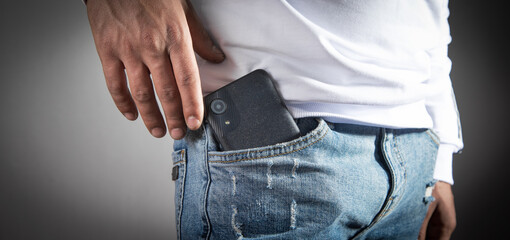 Man putting smartphone in pocket of jeans.