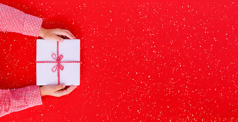 banner gift box in children's hands on a red background, presenting a gift