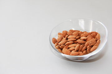 grains of natural brown almonds in a transparent glass plate