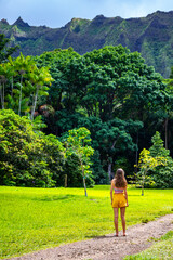 beautiful girl walks through Ho'omaluhia Botanical Garden admiring the mighty mountains on oahu, hawaiian islands; holiday in hawaii