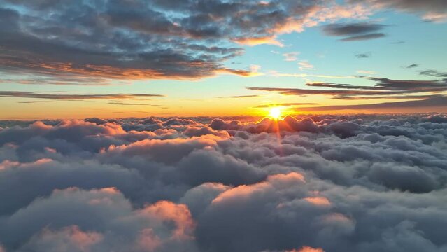 Epic sunset over the clouds. Warm sun sets over the horizon in clouds. Flight in the sky at sunset, view from window of airplane. UHD, 4K