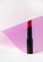 Beautiful red lipstick on white and pink background. Professional makeup product. Lipstick still life on pastel background.