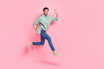Fototapeta na wymiar Full length photo of funny cheerful man wear stylish clothes go empty space arm demonstrate hi symbol isolated on pink color background
