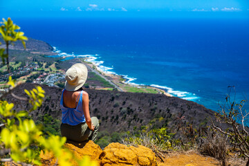 girl in a hat enjoys the oahu panorama from the top of the famous koko crater railway trailhead,...