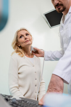 low angle view of mature woman near doctor doing ultrasound examination on blurred foreground.