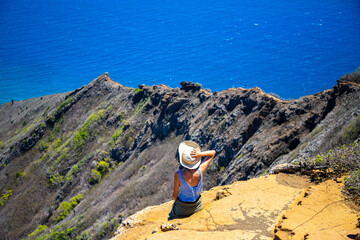 Fototapeta na wymiar girl in a hat enjoys the oahu panorama from the top of the famous koko crater railway trailhead, oahu, hawaii, hiking in hawaii, holiday in hawaii