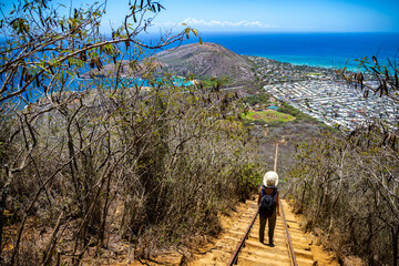 backpacker girl in hat hiking on steps of famous koko crater railway trailhead, oahu, hawaii,...