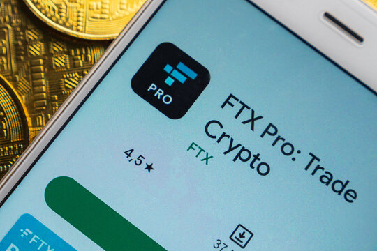 The FTX cryptocurrency exchange apps on a smartphone screen, which is lying on bitcoin coins. The concept of FTX bankruptcy and collapse.