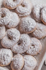 Fototapeta na wymiar A lot of round donuts with powdered sugar on a cream enameled baking sheet.