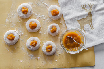 Cookies with apricot jam before baking on a yellow silicone mat
