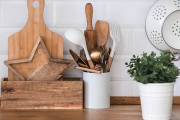 Dishes and cutlery on the kitchen wooden countertop, ready to cook. White modern kitchen in Scandinavian style, kitchen details.
