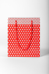 Bright red polka dot gift bag on a white background.