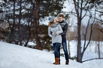 The couple hugs and smiles while standing in the snow.