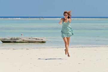 Fototapeta premium Young pretty woman on the tropical sandy beach with turquoise water sea background, Zanzibar 