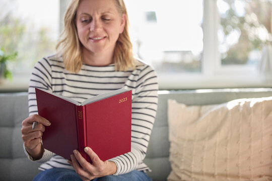 Mature Woman Holding New Year 2023 Diary At Home