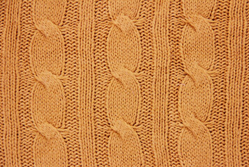 the texture of an orange woolen fabric knitted from threads with a pigtail pattern