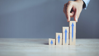 businessman hand  arranging wood block stacking as step stair with arrow up.concept for business growth success process.