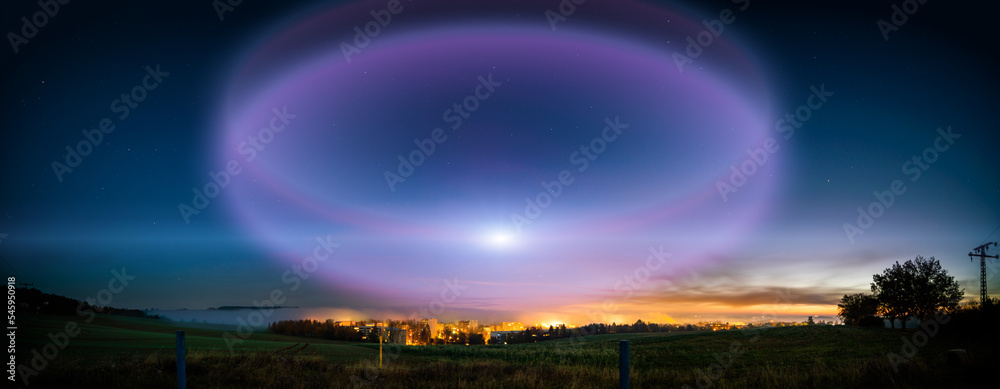 Poster lunar halo in the night sky and city light on the horizon