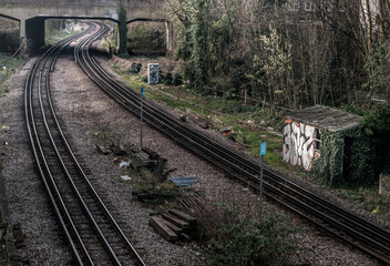 Obraz premium Two old railway tracks stretching into passing under the bridge. Perspective of routes and railroad train tracks in london, Selective focus.
