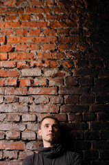 young man in a black jacket against the background of a brown, red and black brick wall
