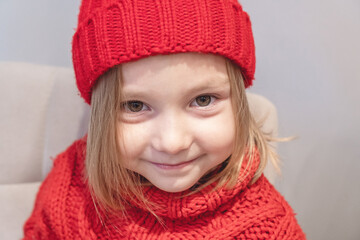 Close-up of a four-year-old girl in a red cap and red sweater. Christmas concept