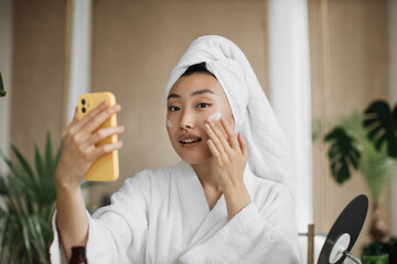 Close up portrait of happy asian woman holding bowl applying white mask homemade moisturizing and nourishing face mask or cream making mixture with natural cosmetic products.