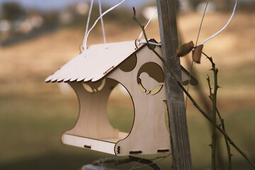Wooden bird feeder in nature with a blurred background. Bird feeding.