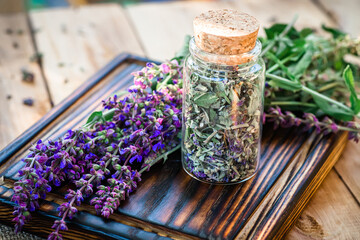 Obraz na płótnie Canvas A glass jar full of dried sage flowers prepared for the manufacture of tinctures or potions for alternative medicine by herbalists or pharmacists.