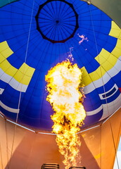 Obraz premium Filling a balloon with hot air from a burning gas burner in summer